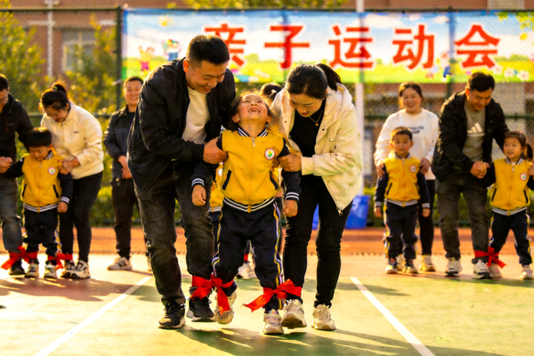 亲子运动会上，家长和孩子共同参与两人三足比赛，其乐融融
