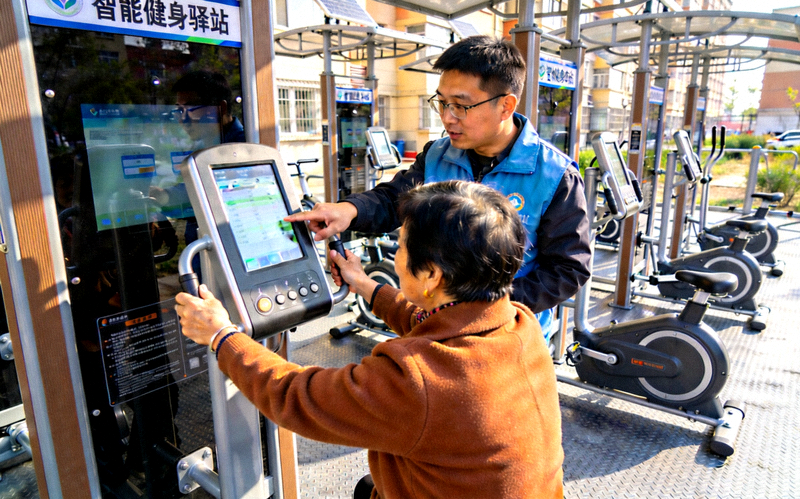 某社区新建的智能健身驿站正式启用，居民正在工作人员指导下体验新器械