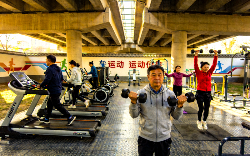 北京市朝阳区某社区利用高架桥下空间改造的全民健身中心，居民正在锻炼