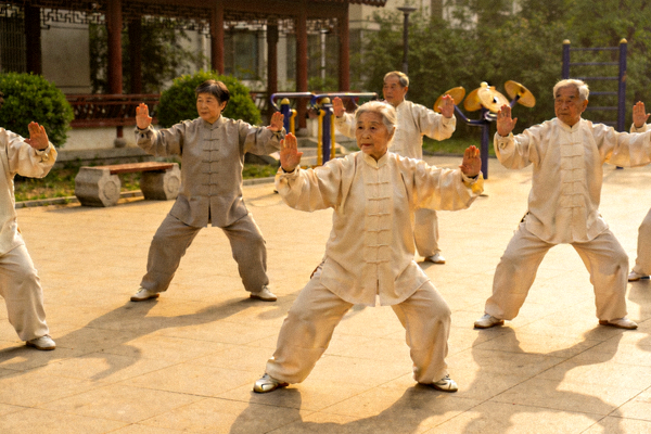 老年人在社区广场上练习太极拳，动作舒缓整齐，体现传统养生文化