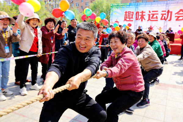 社区居民参与趣味运动会的拔河比赛，气氛热烈