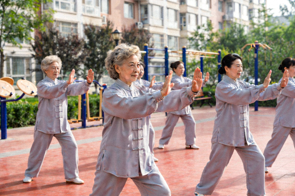 几位老年女性在社区广场上整齐地练习太极拳