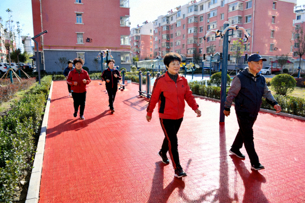老旧小区改造后崭新的塑胶健身步道，居民在步道上健步走