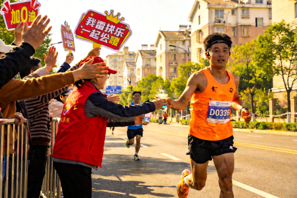 市民在赛道旁为参赛者热情加油助威，志愿者为跑者递送补给水，展现社区互助精神