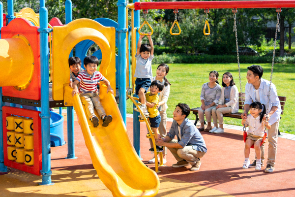 孩子们在社区新建的彩色游乐设施上快乐玩耍，家长在一旁看护