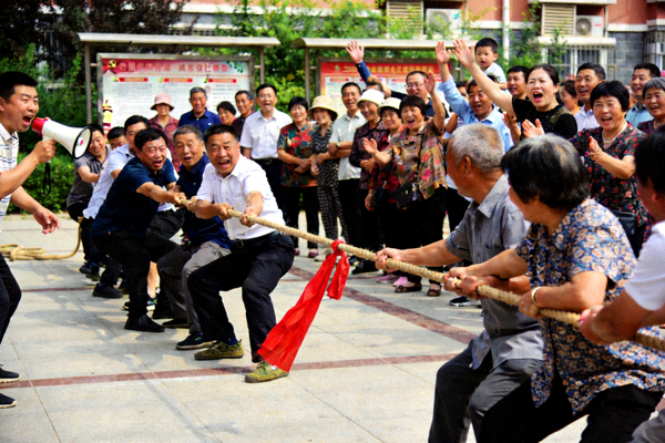 社区拔河比赛激烈进行中，两队居民全力以赴，周围观众呐喊助威