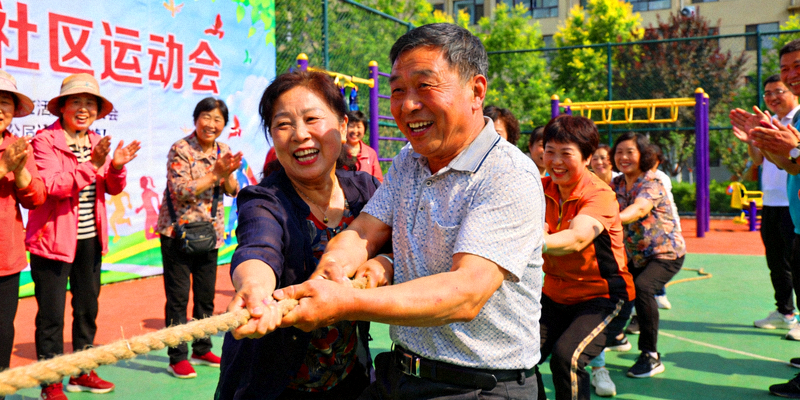 社区居民在运动会上参与趣味拔河比赛，气氛热烈，展现全民健身热潮